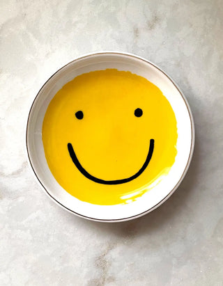 Smiley Trinket Dish - Holt x Palm -  Our ceramic trinket dishes are the perfect catchall for your nightstand or dresser. White ceramic is adorned with our colorful, hand-painted designs, and we lined the edge in metallic gold for added flair. Perfectly packaged in plastic-free gift boxes, pretty enough to give without wrapping! €¢ 3.75€³ ROUND DISH €¢ CERAMIC WITH GOLD DETAILING €¢ PLASTIC-FREE GIFT BOX